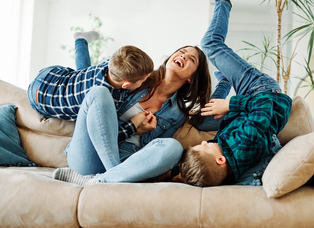 Personal Insurance - Mother and Her Two Sons Having Fun on the Living Room Couch at Home